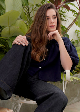 Woman sitting outdoors with plants in the background